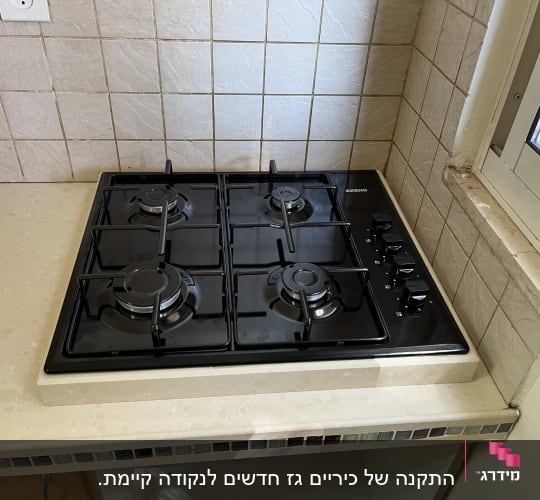 כיריים גז שחורות עם ארבעה מבערים וכפתורי שליטה